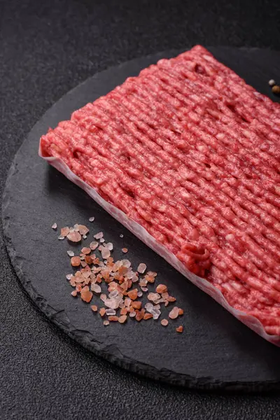 Koyu beton arka planda çiğ et veya tuzlu ve baharatlı domuz eti.