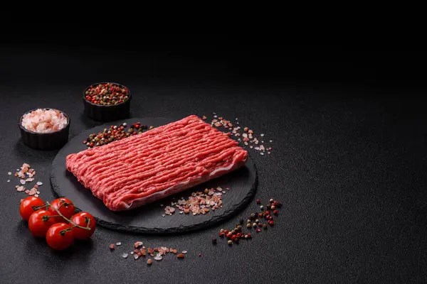 Koyu beton arka planda çiğ et veya tuzlu ve baharatlı domuz eti.