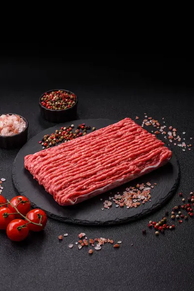 Koyu beton arka planda çiğ et veya tuzlu ve baharatlı domuz eti.