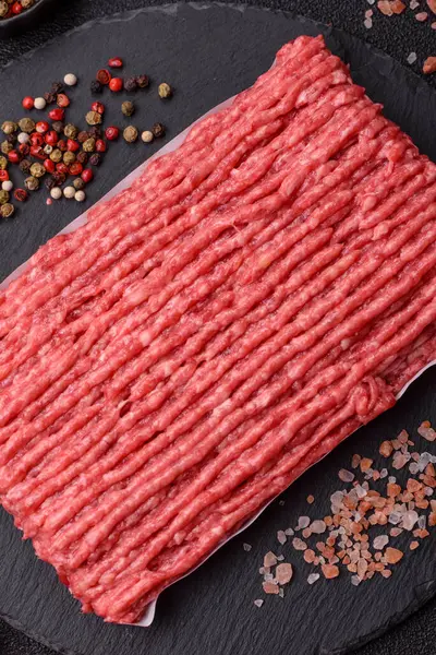 Koyu beton arka planda çiğ et veya tuzlu ve baharatlı domuz eti.