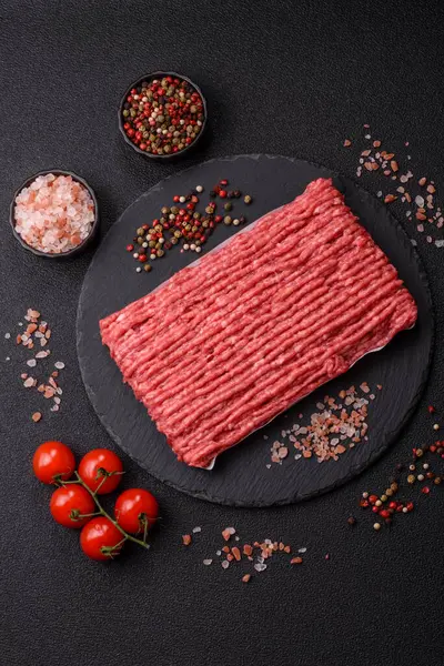 Koyu beton arka planda çiğ et veya tuzlu ve baharatlı domuz eti.