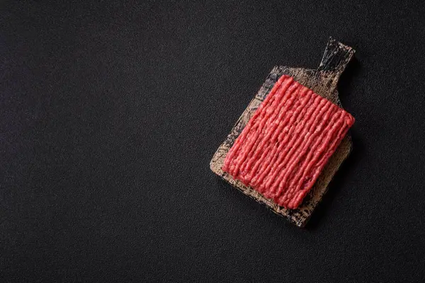 Koyu beton arka planda çiğ et veya tuzlu ve baharatlı domuz eti.