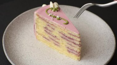 Koyu beton arka planda çilek aromalı pembe katmanlı bir pasta.