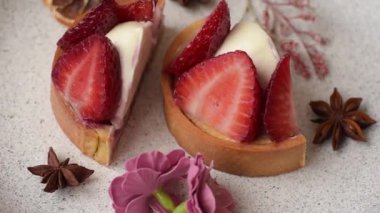 Çilek parçalı yuvarlak tatlı tart ve koyu beton arka planda krema