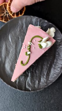Koyu beton arka planda çilek aromalı pembe katmanlı bir pasta.