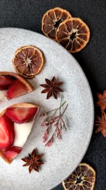 Çilek parçalı yuvarlak tatlı tart ve koyu beton arka planda krema