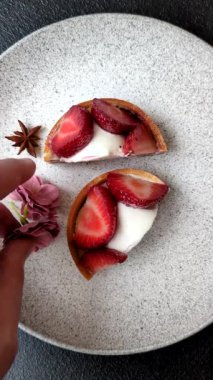 Çilek parçalı yuvarlak tatlı tart ve koyu beton arka planda krema
