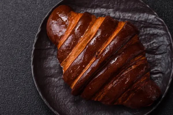 Koyu beton arka planda çikolatalı taze kruvasan.