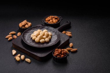 Koyu beton arka planda seramik kasede soyulmuş macadamia cevizi. Besin kaynağı olarak fındık