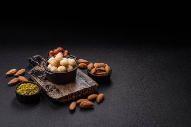 Koyu beton arka planda seramik kasede soyulmuş macadamia cevizi. Besin kaynağı olarak fındık