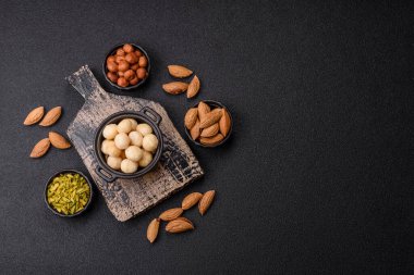 Koyu beton arka planda seramik kasede soyulmuş macadamia cevizi. Besin kaynağı olarak fındık