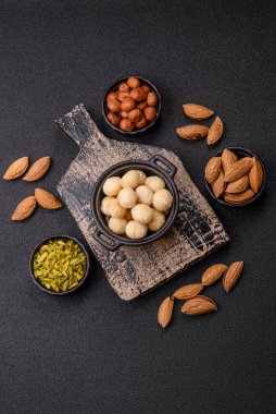 Koyu beton arka planda seramik kasede soyulmuş macadamia cevizi. Besin kaynağı olarak fındık