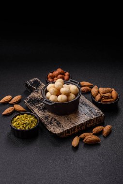 Koyu beton arka planda seramik kasede soyulmuş macadamia cevizi. Besin kaynağı olarak fındık