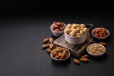 Koyu beton arka planda seramik kasede soyulmuş macadamia cevizi. Besin kaynağı olarak fındık