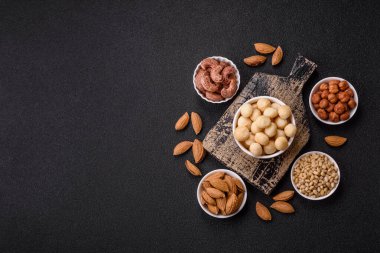 Koyu beton arka planda seramik kasede soyulmuş macadamia cevizi. Besin kaynağı olarak fındık