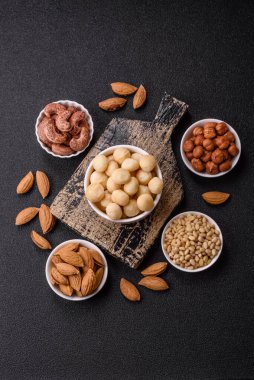 Koyu beton arka planda seramik kasede soyulmuş macadamia cevizi. Besin kaynağı olarak fındık