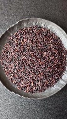 Seramik bir kasede kırmızı veya kahverengi çiğ pirinç. Pirinç Asya organik gıdasının bir malzemesidir.