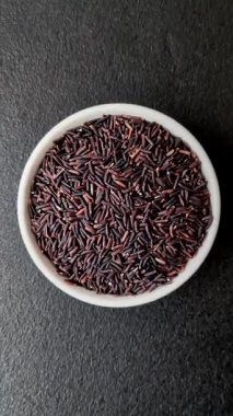 Seramik bir kasede kırmızı veya kahverengi çiğ pirinç. Pirinç Asya organik gıdasının bir malzemesidir.