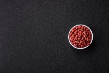 Koyu beton arka planda bir kasede yer fıstığı ya da kabuğu soyulmuş graundnut. Protein kaynağı olarak fındık