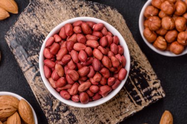 Koyu beton arka planda bir kasede yer fıstığı ya da kabuğu soyulmuş graundnut. Protein kaynağı olarak fındık