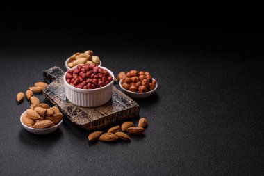 Koyu beton arka planda bir kasede yer fıstığı ya da kabuğu soyulmuş graundnut. Protein kaynağı olarak fındık