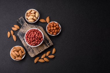 Koyu beton arka planda bir kasede yer fıstığı ya da kabuğu soyulmuş graundnut. Protein kaynağı olarak fındık