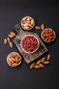 Koyu beton arka planda bir kasede yer fıstığı ya da kabuğu soyulmuş graundnut. Protein kaynağı olarak fındık