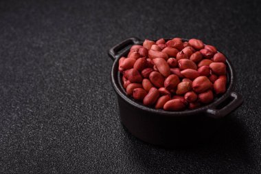 Koyu beton arka planda bir kasede yer fıstığı ya da kabuğu soyulmuş graundnut. Protein kaynağı olarak fındık