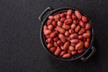 Koyu beton arka planda bir kasede yer fıstığı ya da kabuğu soyulmuş graundnut. Protein kaynağı olarak fındık