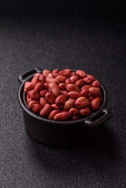 Koyu beton arka planda bir kasede yer fıstığı ya da kabuğu soyulmuş graundnut. Protein kaynağı olarak fındık