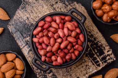 Koyu beton arka planda bir kasede yer fıstığı ya da kabuğu soyulmuş graundnut. Protein kaynağı olarak fındık