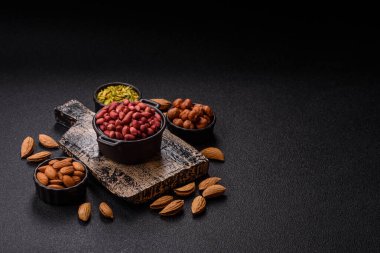 Koyu beton arka planda bir kasede yer fıstığı ya da kabuğu soyulmuş graundnut. Protein kaynağı olarak fındık