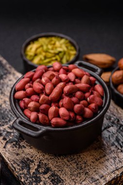 Koyu beton arka planda bir kasede yer fıstığı ya da kabuğu soyulmuş graundnut. Protein kaynağı olarak fındık