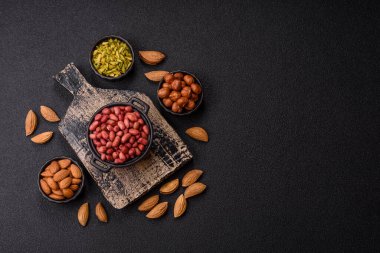 Koyu beton arka planda bir kasede yer fıstığı ya da kabuğu soyulmuş graundnut. Protein kaynağı olarak fındık