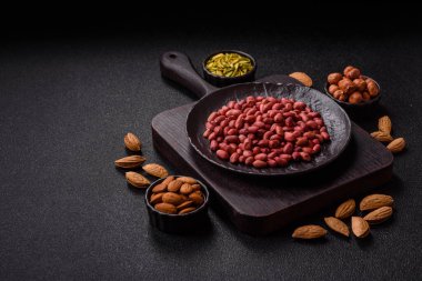 Koyu beton arka planda bir kasede yer fıstığı ya da kabuğu soyulmuş graundnut. Protein kaynağı olarak fındık