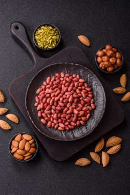 Koyu beton arka planda bir kasede yer fıstığı ya da kabuğu soyulmuş graundnut. Protein kaynağı olarak fındık