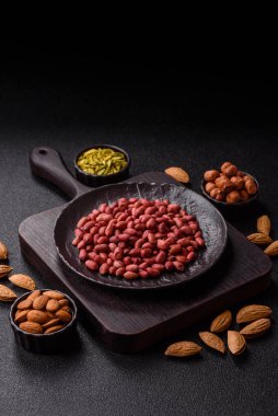 Koyu beton arka planda bir kasede yer fıstığı ya da kabuğu soyulmuş graundnut. Protein kaynağı olarak fındık