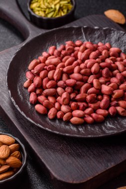 Koyu beton arka planda bir kasede yer fıstığı ya da kabuğu soyulmuş graundnut. Protein kaynağı olarak fındık