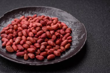 Koyu beton arka planda bir kasede yer fıstığı ya da kabuğu soyulmuş graundnut. Protein kaynağı olarak fındık