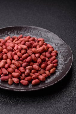 Koyu beton arka planda bir kasede yer fıstığı ya da kabuğu soyulmuş graundnut. Protein kaynağı olarak fındık