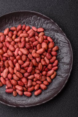 Koyu beton arka planda bir kasede yer fıstığı ya da kabuğu soyulmuş graundnut. Protein kaynağı olarak fındık