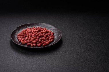 Koyu beton arka planda bir kasede yer fıstığı ya da kabuğu soyulmuş graundnut. Protein kaynağı olarak fındık