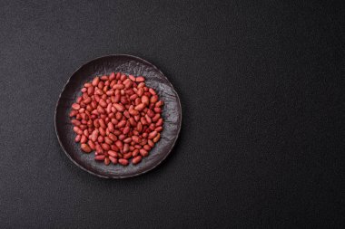 Koyu beton arka planda bir kasede yer fıstığı ya da kabuğu soyulmuş graundnut. Protein kaynağı olarak fındık