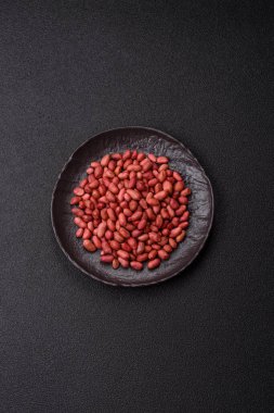 Koyu beton arka planda bir kasede yer fıstığı ya da kabuğu soyulmuş graundnut. Protein kaynağı olarak fındık