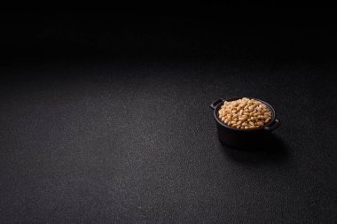 Koyu beton arka planda bir kasede soyulmuş çam fıstığı. Protein kaynağı olarak fındık.