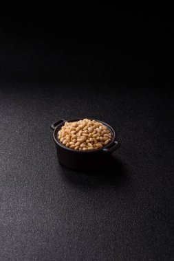 Koyu beton arka planda bir kasede soyulmuş çam fıstığı. Protein kaynağı olarak fındık.