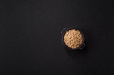 Koyu beton arka planda bir kasede soyulmuş çam fıstığı. Protein kaynağı olarak fındık.