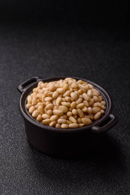 Koyu beton arka planda bir kasede soyulmuş çam fıstığı. Protein kaynağı olarak fındık.