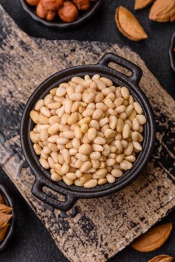 Koyu beton arka planda bir kasede soyulmuş çam fıstığı. Protein kaynağı olarak fındık.