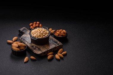 Koyu beton arka planda bir kasede soyulmuş çam fıstığı. Protein kaynağı olarak fındık.